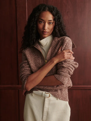 A person wearing a VARLEY - SHERIDA HALF-ZIP KNIT SWEATER IN GINGERBREAD FLECK, a brown speckled boucle yarn sweater with a collared half-zip neckline.