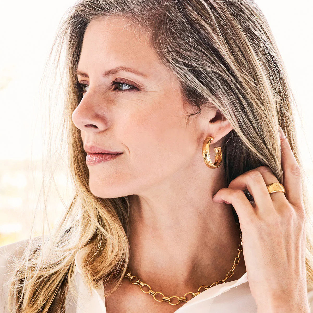 The CAPUCINE DE WULF Cleopatra Classic Medium Hoop Earrings feature a hammered gold finish, textured surface, and a subtle red dot on the inner edge. Shown from front and side views. Anti-tarnish coating ensures lasting shine.
