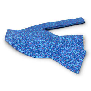 The BIRD DOG BAY PETER-BLAIR Zinnia Silk Bow Tie in aqua and purple features a floral print, is handmade with an adjustable neck for a perfect fit, and is displayed against a white background.