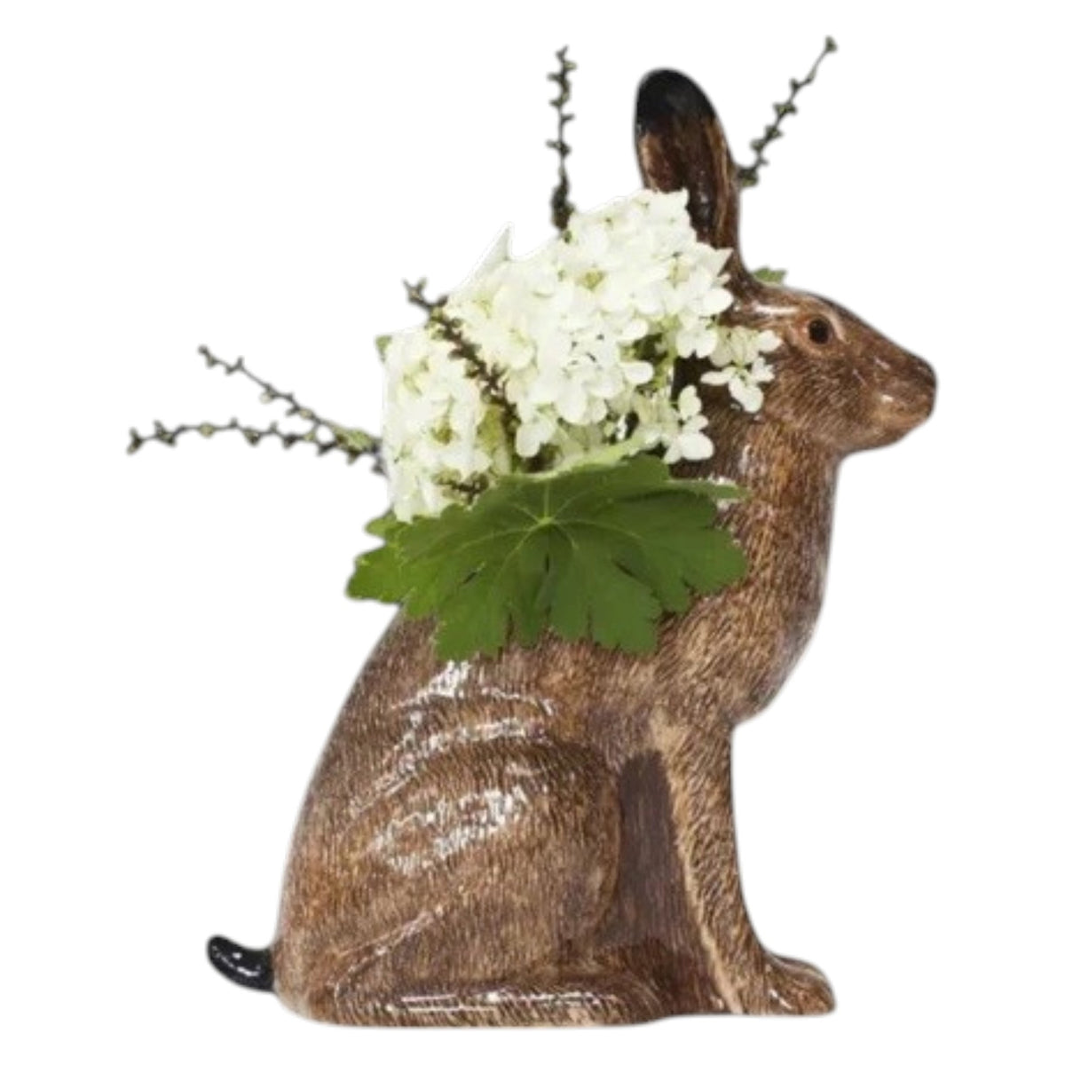 The QUAIL CERAMICS - HARE VASE, LARGE by QUAIL DESIGNS is a hand-painted brown ceramic vase shaped like a hare, displayed with yellow and white flowers and greenery. A single yellow flower lies beside it on a white background.