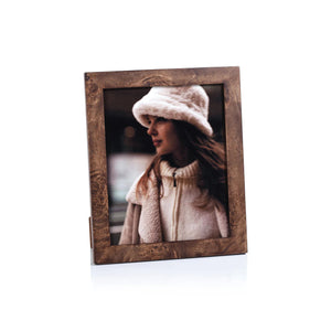 The ZODAX BURL WOOD PHOTO FRAME 8X10 showcases a portrait of a woman in a white fuzzy hat and cream coat, gazing sideways against a softly blurred backdrop.