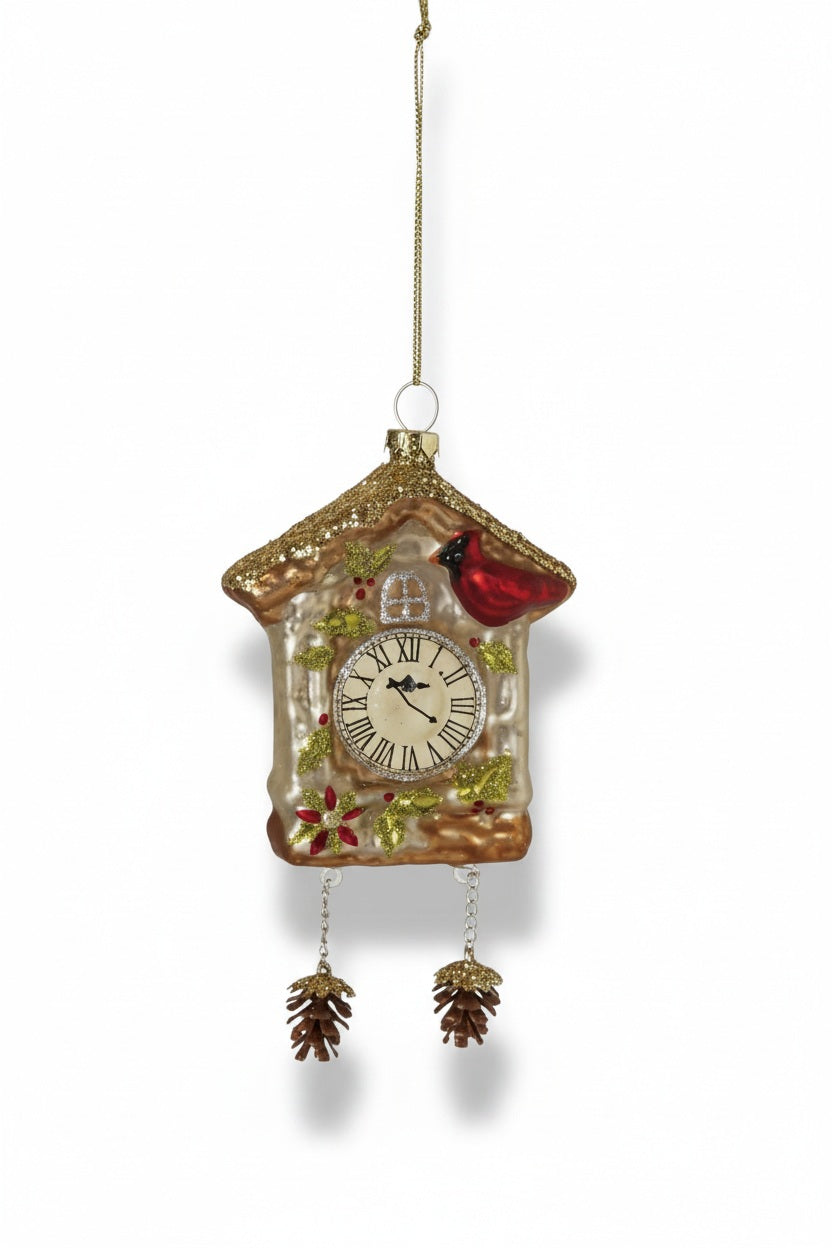 Creative Co-op hand painted glass cuckoo clock ornament decorated with a red cardinal, holly leaves, and two dangling pine cone weights.