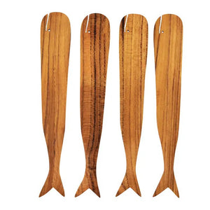 The BE HOME - TEAK WHALE SPREADERS by BE HOME, INC rest on a round white marble cutting board with a hole at the top, displayed on a wooden surface.