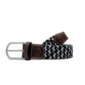 The ROOSTAS BAJA Woven Stretch Belt features a black, white, and gray tri-color weave, silver buckle, brown leather with white stitching, and an embossed ROOSTAS logo.