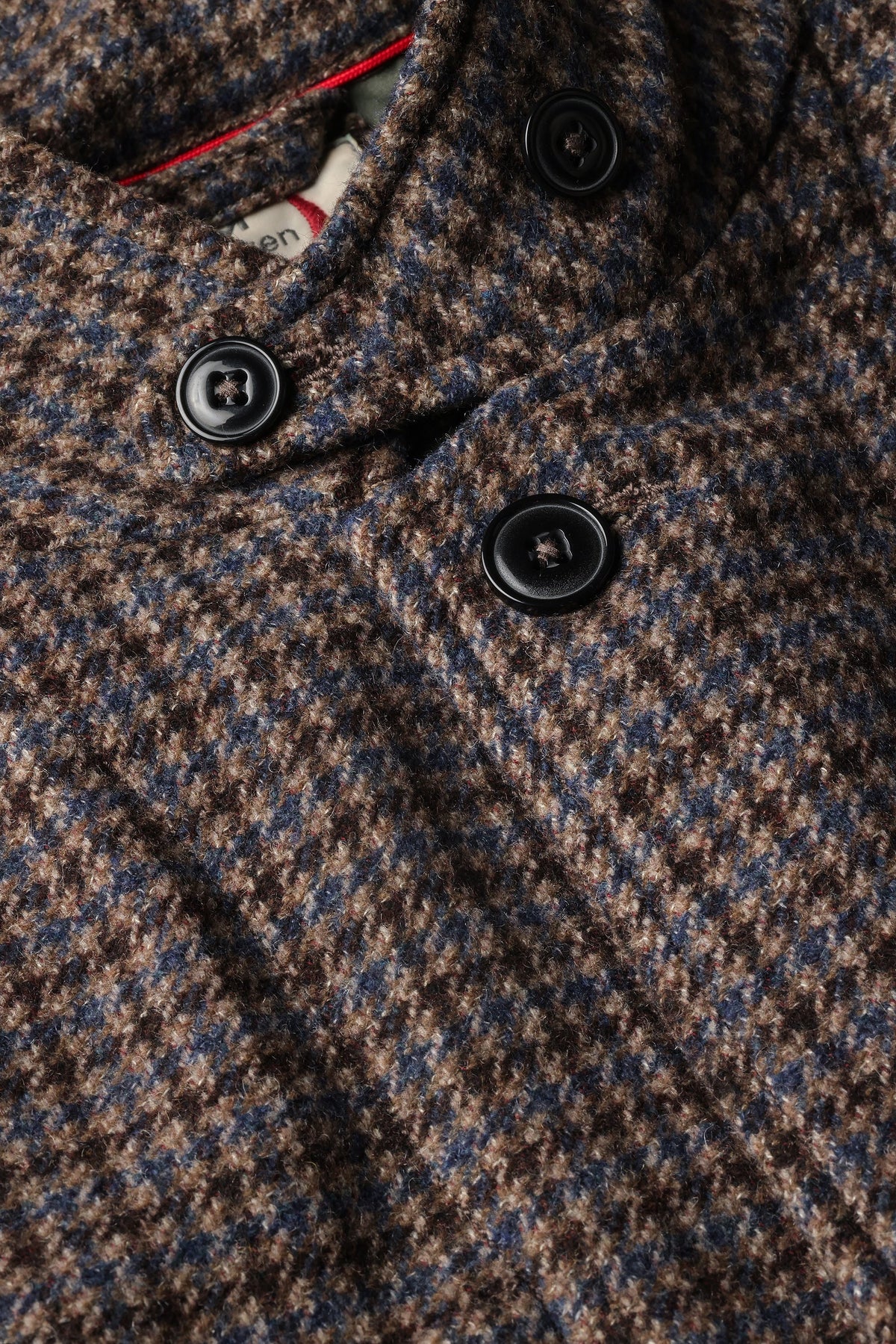 The RELWEN Heritage Trap Blazer in Brown and Blue Check features a brown and black plaid pattern, reminiscent of a classic check blazer, shown from the back with buttoned cuffs and a subtly wrinkled texture, laid flat on a white background.