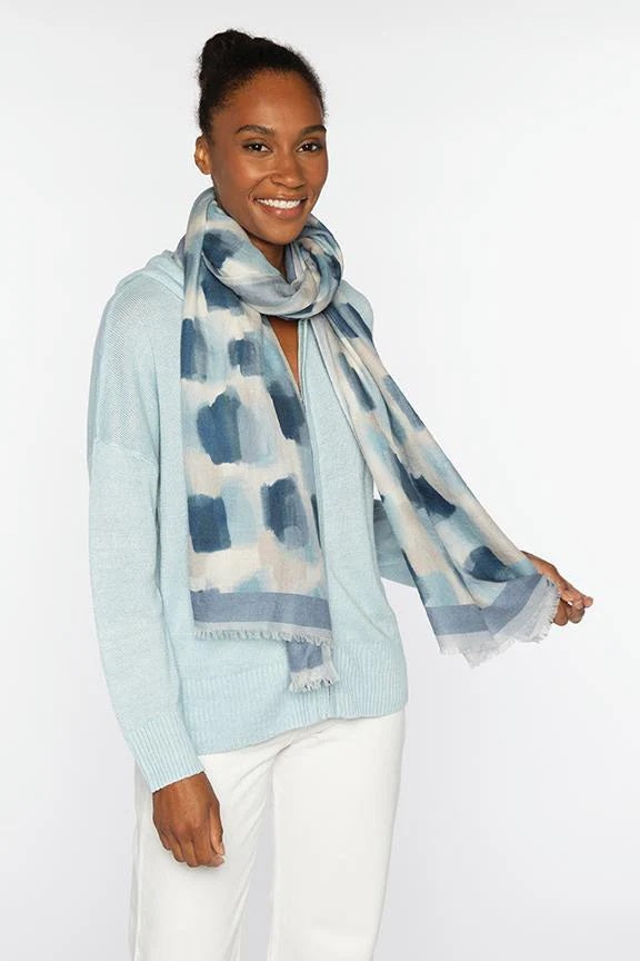 The KINROSS CASHMERE - BRUSHSTROKE PRINT CASHMERE SCARF by KINROSS features a lightweight, translucent fabric with a beige and white abstract geometric pattern and slightly frayed edges, displayed hanging to highlight its length.