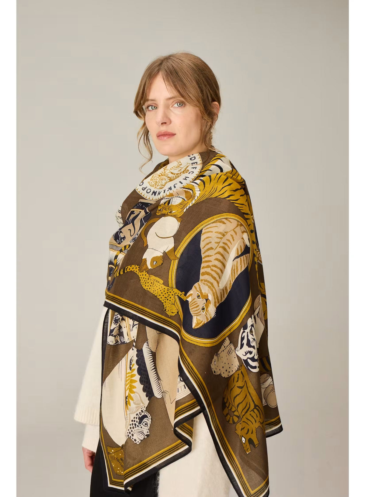 The INOUI EDITIONS - COLLECTIONNEUR Wool Scarf with Cats in Khaki by INOUI is a rectangular accessory crafted in India from 100% wool. It features an artistic collage-like pattern of illustrated cats and circular motifs in shades of gold, white, black, and gray set against a dark khaki background. Measuring 70 x 190 cm, this striking scarf adds both warmth and a touch of artistry to any ensemble.