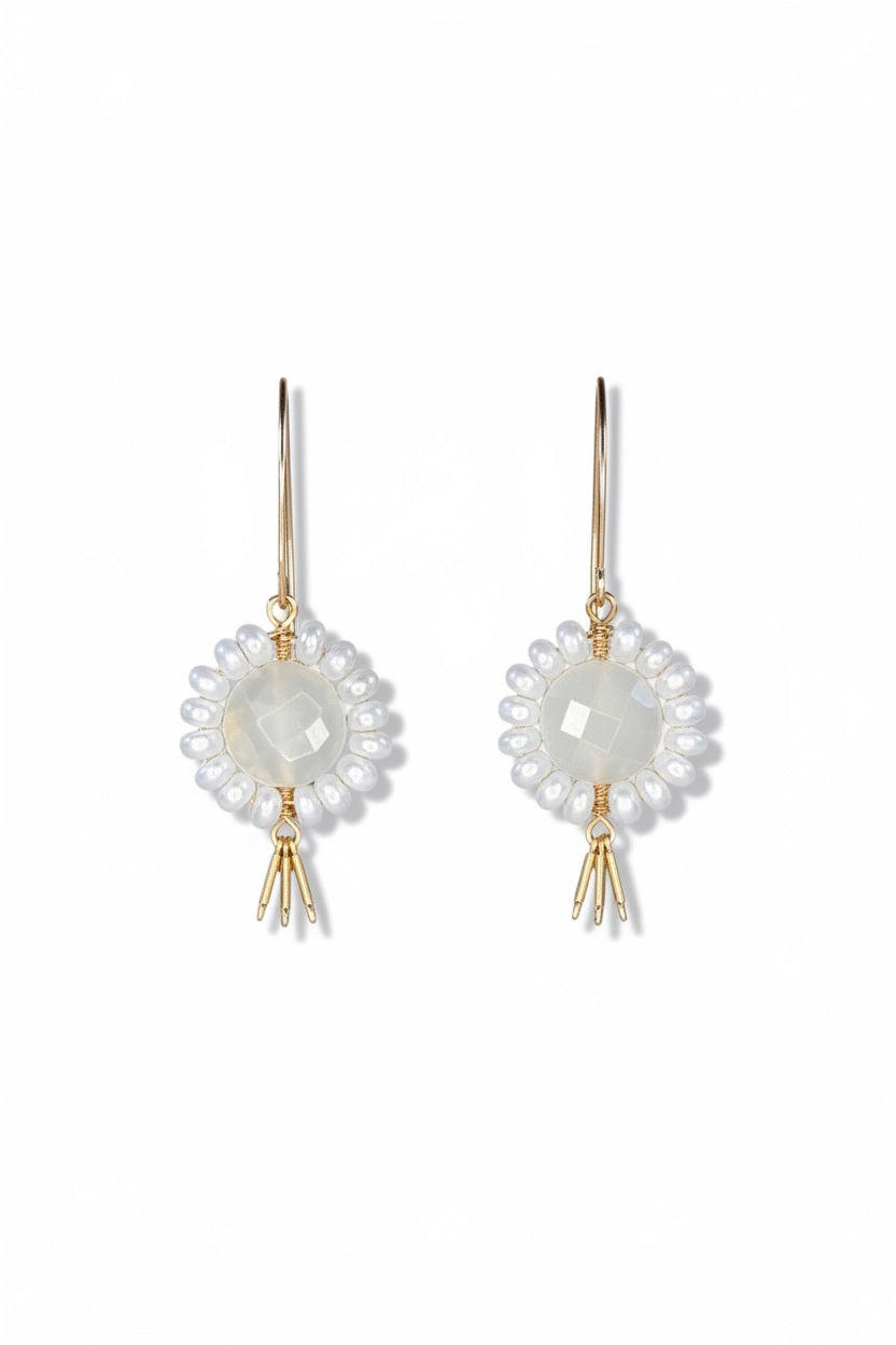 The GOLDISH - Floral Gemstone Earrings in Moonstone and White Pearl feature a circular, faceted moonstone center surrounded by white pearls, with three gold danglers, all set in 14K gold fill. Displayed on a white stand against a dark background.