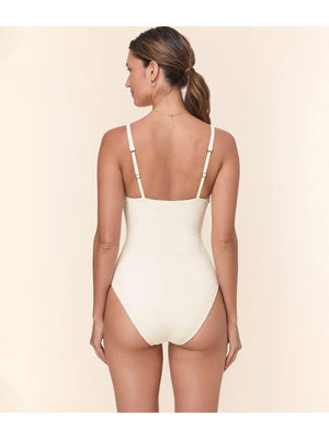 A woman wears the ANDIE SWIM The Amalfi Swimsuite in Textured Weave Gardenia, featuring a scoop neck and adjustable straps, accessorized with a gold necklace. Only her upper body and part of her face are shown against a neutral background.