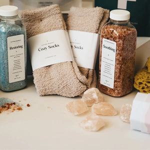 Beige fuzzy socks made from soft plush material are wrapped in a white "Cozy Cloud Socks" label displaying "Giften Market" and "GIFTENMARKET.COM." These women's socks are neatly folded and viewed from above on a plain background.