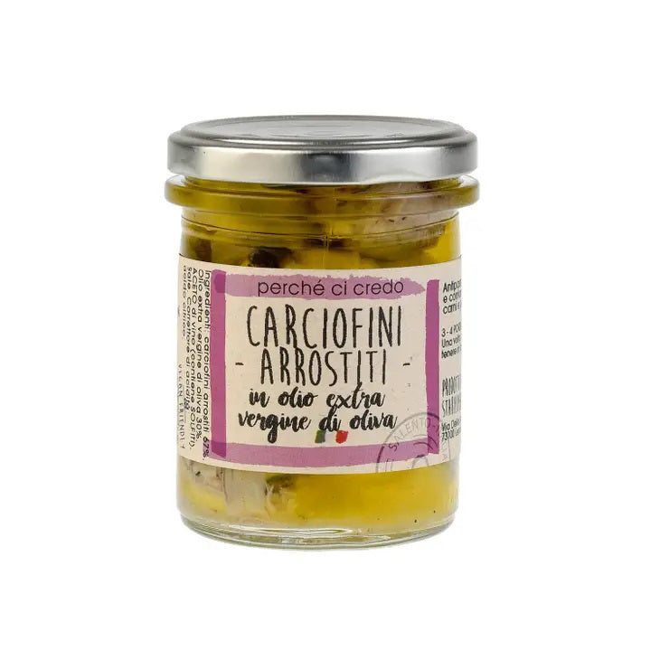 A jar of "PERCHE CI CREDO - Grilled Artichokes" with a metal lid from the brand ZIA PIA IMPORTS. The label, predominantly pink and white, features images of Italian grilled artichokes in the background. Filled with tender artichokes in extra virgin olive oil, this pantry staple is perfect for any meal.