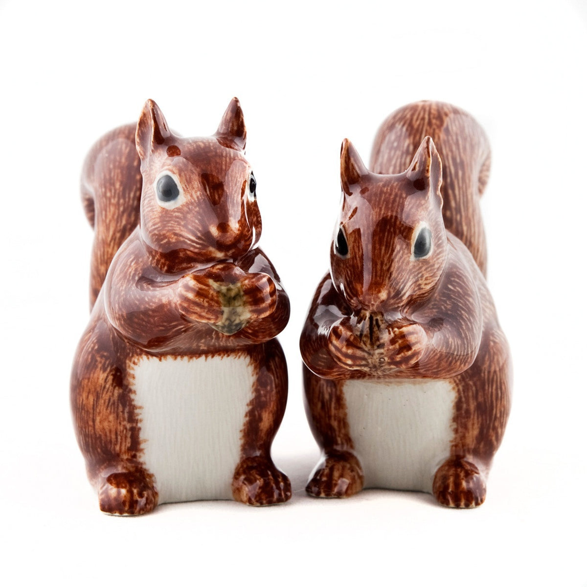 The QUAIL CERAMICS SQUIRREL SALT AND PEPPER shakers from QUAIL DESIGNS feature two handpainted stoneware squirrels with brown fur and white bellies, standing upright and holding food. They're both charming and dishwasher safe.