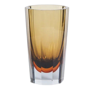 The CORVATSCH Amber and Smoke Tonal Glass Vase by ZODAX, measuring 8.25”, features elegant amber-brown gradients and a faceted design—perfect for enhancing your home decor or complementing modern vase arrangements on a light, textured surface with a neutral backdrop.