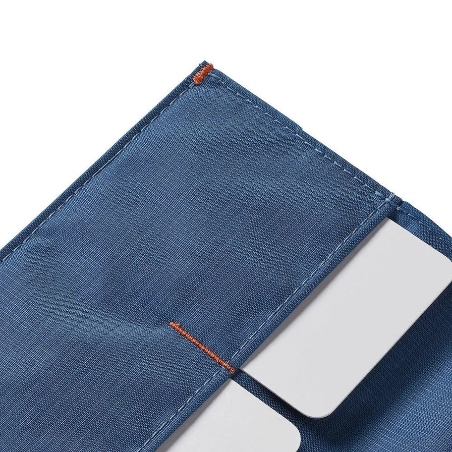 The ALLETT - THE ORIGINAL WALLET in RFID-blocking indigo blue nylon features four card slots, a cash pocket, and an orange no-slip card grip detail shown in a close-up inset. Text below reads "no-slip card grip.