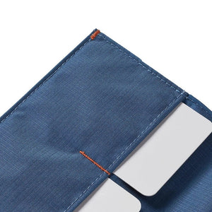 The ALLETT - THE ORIGINAL WALLET in RFID-blocking indigo blue nylon features four card slots, a cash pocket, and an orange no-slip card grip detail shown in a close-up inset. Text below reads "no-slip card grip.