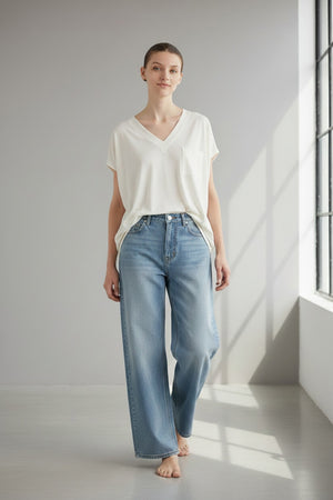 A person wearing dark sunglasses, white pants, and the MEIMEIJ Oversized Cotton T-shirt in White with a boxy silhouette and short sleeves stands against a plain light background, hair pulled back.