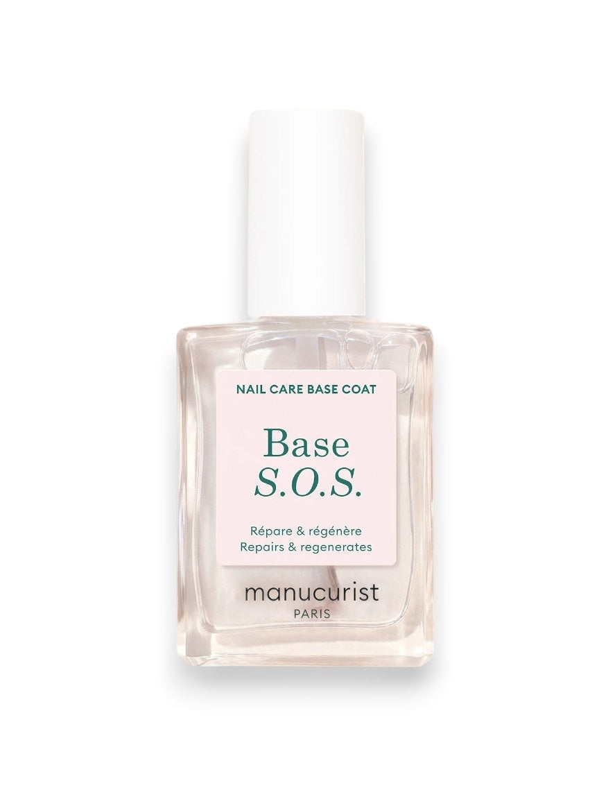 A close-up of the MANUCURIST - S.O.S. NAIL STRENGTHENER BASE COAT by MANUCURIST INC being applied, with text highlighting AHA for exfoliation, Vitamin C for protection, Vitamin B5 for hydration, and Hexanol for repair. Soft pink leaf background.