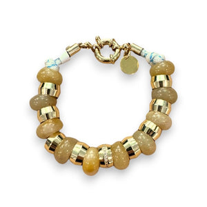 The HOLST & LEE - SEMI PRECIOUS BRACELET by HOLST & LEE is a chic accessory featuring alternating round, metallic gold and translucent brown beads. It has a unique clasp and a small, circular charm hanging from it. The evenly spaced and polished beads give it a stylish and elegant look.