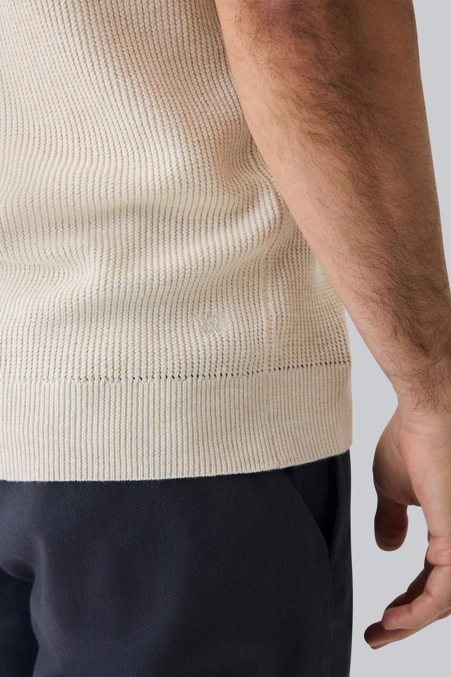 A man with dark hair and a short beard models the MACK WELDON Tech Linen Button Up Sweater Polo in Latte Heather, standing hands-in-pockets against a white background and looking effortlessly stylish and comfortable.