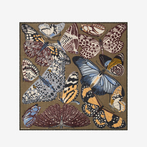The INOUI EDITIONS - PAPILLONS WOOL SCARF IN KHAKI by INOUI is a square scarf made in India, featuring an intricate and colorful butterfly pattern in brown, blue, yellow, and white hues on a tan background. Measuring 130 x 130 cm, it provides generous coverage and stylish versatility for any occasion.