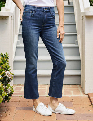 A pair of FRANK & EILEEN - Killian Crop Flare Jeans is displayed flat against a textured white background. Made from soft denim with power stretch, they feature a classic five-pocket design, belt loops, and a button and zip closure. The high-rise legs are slightly flared, offering a clean, modern appearance.