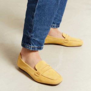 The REQINS - HEMA Suede Loafer in Ochre, expertly crafted by REQINS, features a low heel and a decorative front strap, shown against a plain light background.