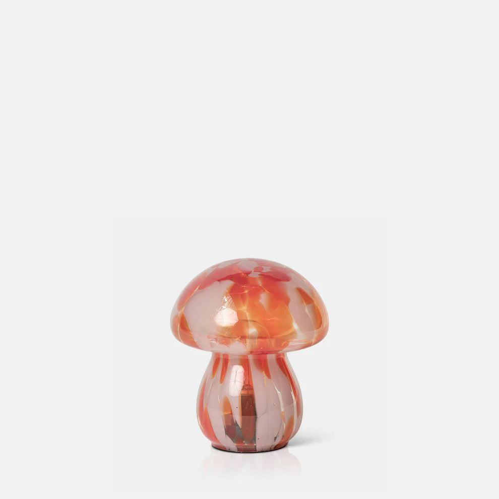 The ABIGAIL AHERN - MUSHROOM CORDLESS LED is a small glass lamp with a rounded cap and stem, featuring swirled pink, orange, and red hues—resembling a charming mushroom figurine against a plain white background.