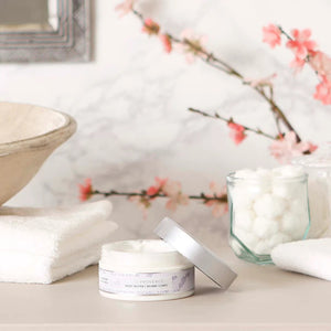 A 200 ml (6.7 fl oz) jar of BODY BUTTER - LAVENDER by EUROPEAN SOAPS, LLC, enriched with shea butter for deep moisturization. The round container features a silver lid and a white label adorned with light lavender illustrations and details about the product in both English and French.