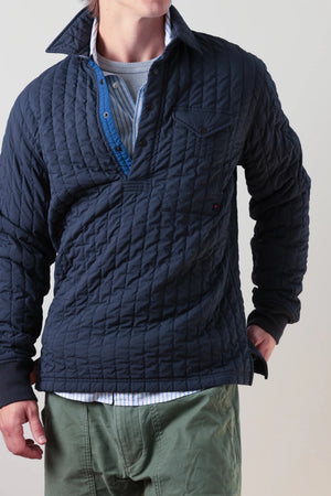 The RELWEN Polo-Jack in Muted Olive, a long-sleeve quilted technical popover featuring a chest pocket, buttoned collar, and cuffs, is shown laying flat on a white background.