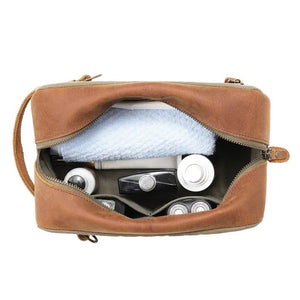 The TSD BRAND Valley Oak Toiletry Bag in olive is a rectangular, handcrafted travel essential made from durable canvas, featuring a tan leather strap and a small leather patch for added style.