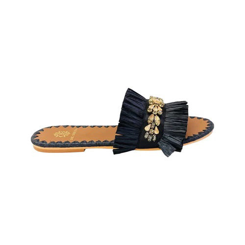 Introducing the DA SIENA Raffia Slides with Crystals from DE SIENA, a stylish pair of summer flats featuring a tan sole and dark blue ruffle strap adorned with intricate gold, pearl, and diamond embellishments in a floral pattern. The edge of the sole boasts a zigzag design in matching dark blue.