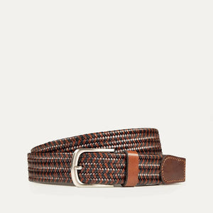 The WILL LEATHER GOODS - STRETCH BELT features a green, purple, and black braided design with full-grain leather accents by the silver buckle and tip, shown on a plain light background. Brand: WILL LEATHER GOODS.