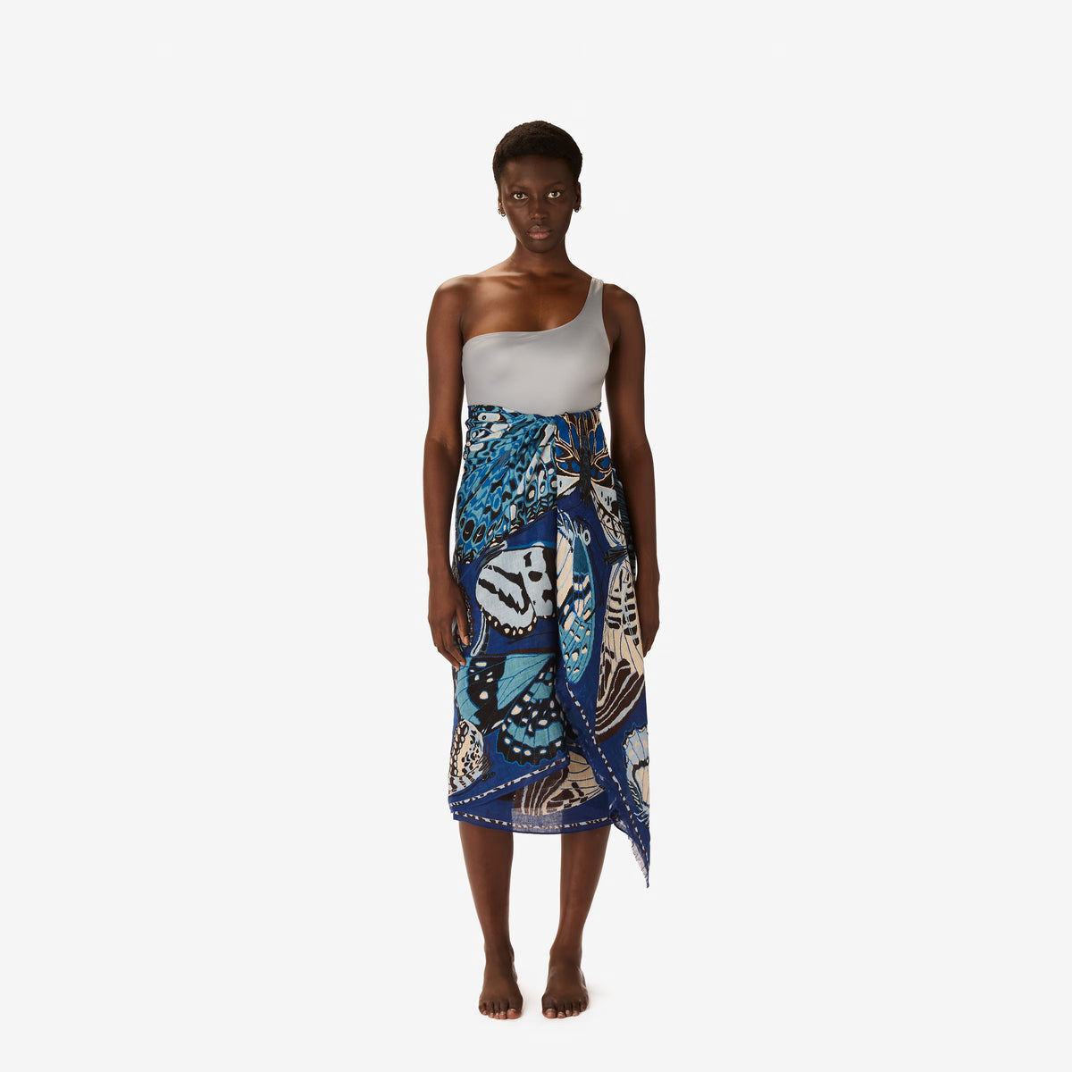The INOUI EDITIONS - PAPILLON SCARF IN NAVY by INOUI showcases a hand-printed butterfly pattern in blue, white, and tan on navy linen, adding an elegant touch to any outfit.