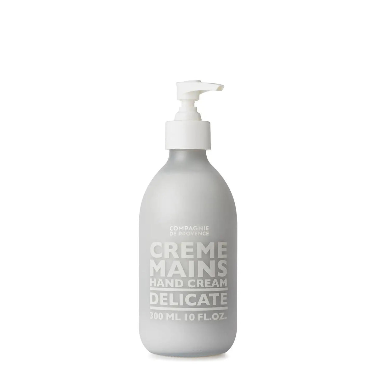 A frosted 10oz glass pump bottle of COMPAGNIE DE PROVENCE - CREME MAINS DELICATE by CIE LUXE BRANDS stands upright on a white background, offering soft skin with nourishing shea butter and a fresh scent.
