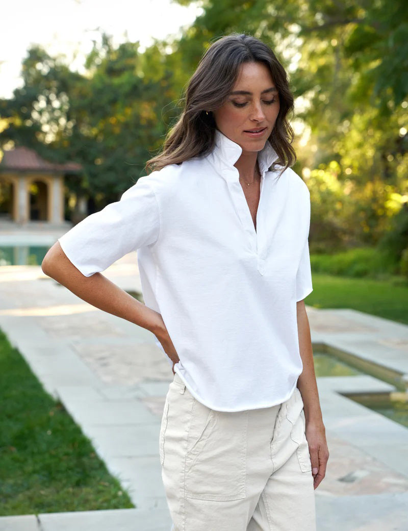 The FRANK &amp; EILEEN Patty Short Sleeve Popover Henley is a plain white collared shirt with a relaxed fit, garment-dyed for softness. It features a subtle v-neck and visible stitching for a casual style.