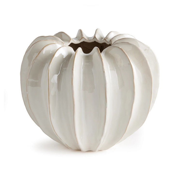 The NAPA HOME AND GARDEN - BLECKLYN POT is a white, glossy ceramic piece with a pumpkin-like form and pleated segments, featuring an artisan touch. Its uneven, scalloped opening evokes the essence of curated coastal-inspired design.