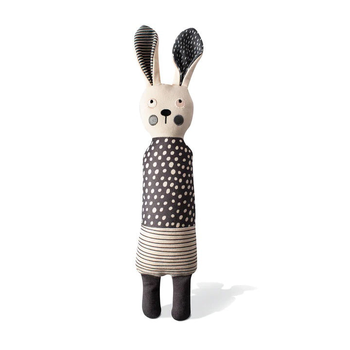 The FRINGE STUDIO - ALL EARS RABBIT CANVAS DOG TOY by PET SHOP BY FRINGE STUDIO is a light-colored fabric doll resembling a rabbit that stands upright. It has long ears, one black and one patterned, with a polka-dot dress combined with striped fabric. Designed for interactive play, the doll features simple facial details with round eyes, a small nose, and pink cheeks.