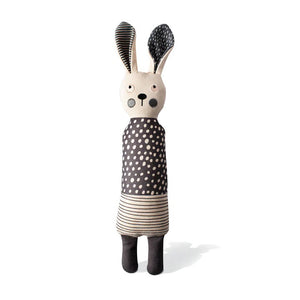 The FRINGE STUDIO - ALL EARS RABBIT CANVAS DOG TOY by PET SHOP BY FRINGE STUDIO is a light-colored fabric doll resembling a rabbit that stands upright. It has long ears, one black and one patterned, with a polka-dot dress combined with striped fabric. Designed for interactive play, the doll features simple facial details with round eyes, a small nose, and pink cheeks.