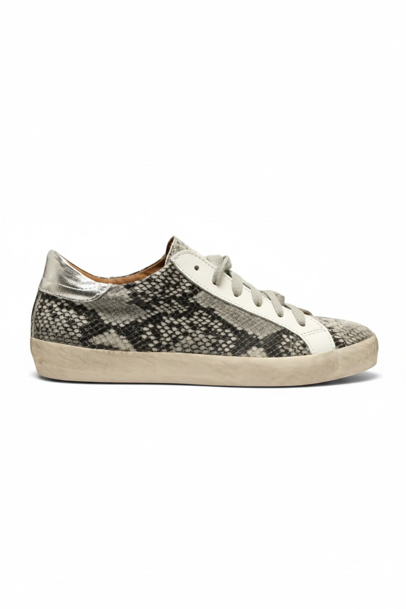 The MICHELE LOPRIORE GEMMA Sneaker in python print is a low-top leather shoe featuring a gray and black snakeskin pattern, white laces, a white side stripe, and a subtly distressed rubber sole, displayed against a plain light background.