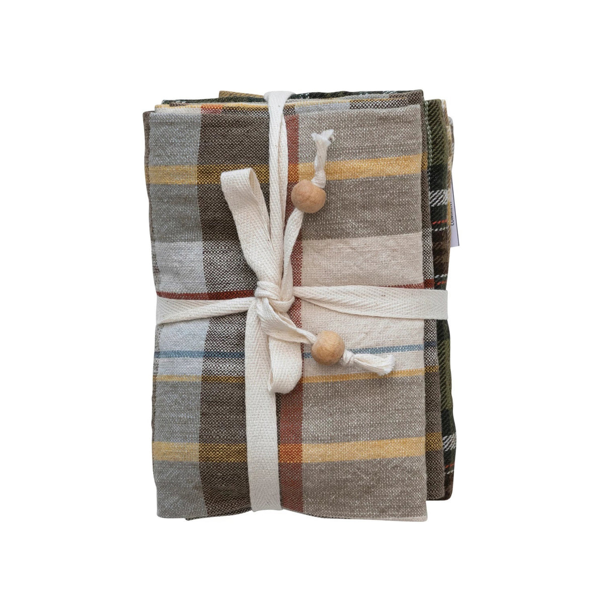 The CREATIVE COOP COTTON PLAID TEA TOWELS - SET OF 3 features brown, beige, yellow, and blue cotton towels folded and tied with a cream fabric ribbon and wooden beads, shown against a white background.