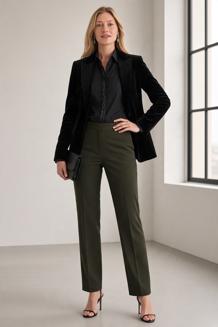 A woman wearing a black HINSON WU - ESTHER LONG SLEEVE SHIRT WITH SEQUIN TRIM under a black velvet blazer, paired with olive green trousers, black high-heeled sandals, and holding a black clutch.