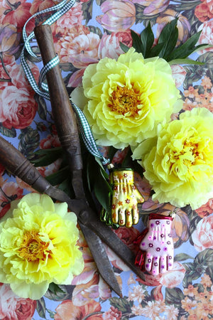 Two GARDENING GLOVES ORNAMENT glass decorations, one pink with purple flowers and one yellow with orange flowers, hanging from gold strings.