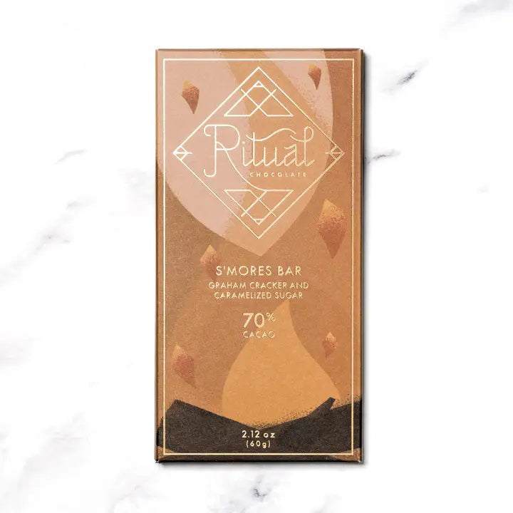 A RITUAL CHOCOLATE - SMORES CHOCOLATE BAR 70% by RITUAL CHOCOLATE, in brown with gold geometric accents and "Graham Cracker and Caramelized Sugar, 70% Cacao" on the label, evokes classic campfire s’mores in every bite.