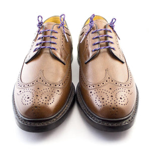 The STOLEN RICHES Dress Shoelace in Bavaria features a coiled blue, red, and white patterned premium nylon lace with silver tips and a branded white label—an eye-catching accessory for dress shoes.