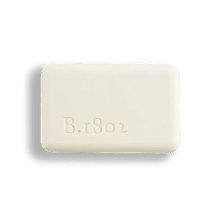 A BEEKMAN - STA ELEMENTS HONEY &amp; ORANGE BLOSSOM 3.5 SOAP bar wrapped in decorative paper featuring orange slices and flowers on a gray and white checkered background.