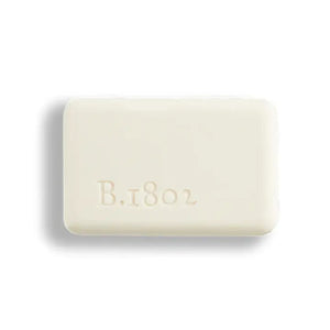 A BEEKMAN - STA ELEMENTS HONEY & ORANGE BLOSSOM 3.5 SOAP bar wrapped in decorative paper featuring orange slices and flowers on a gray and white checkered background.