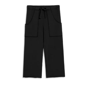 Close-up of a person wearing FRANK & EILEEN Penny Patch Pocket Sweatpant in black, featuring a drawstring waistband and visible stitching. The wearer holds up the waistband slightly against a blurred, light-colored background.