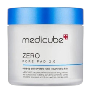 A hand holds a round, textured exfoliating pad above an open jar of KOSMIC KBEAUTY SKINCARE MEDICUBE - ZERO PORE PAD 2.0, 100ML, with its blue lid set aside on a plain white background.