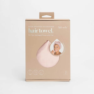 The image displays a beige box with the KITSCH Satin Wrapped Hair Towel inside. The packaging shows an illustration of the towel and a smiling person wearing it, emphasizing its benefits for reducing frizz in damaged, curly, or frizzy hair.