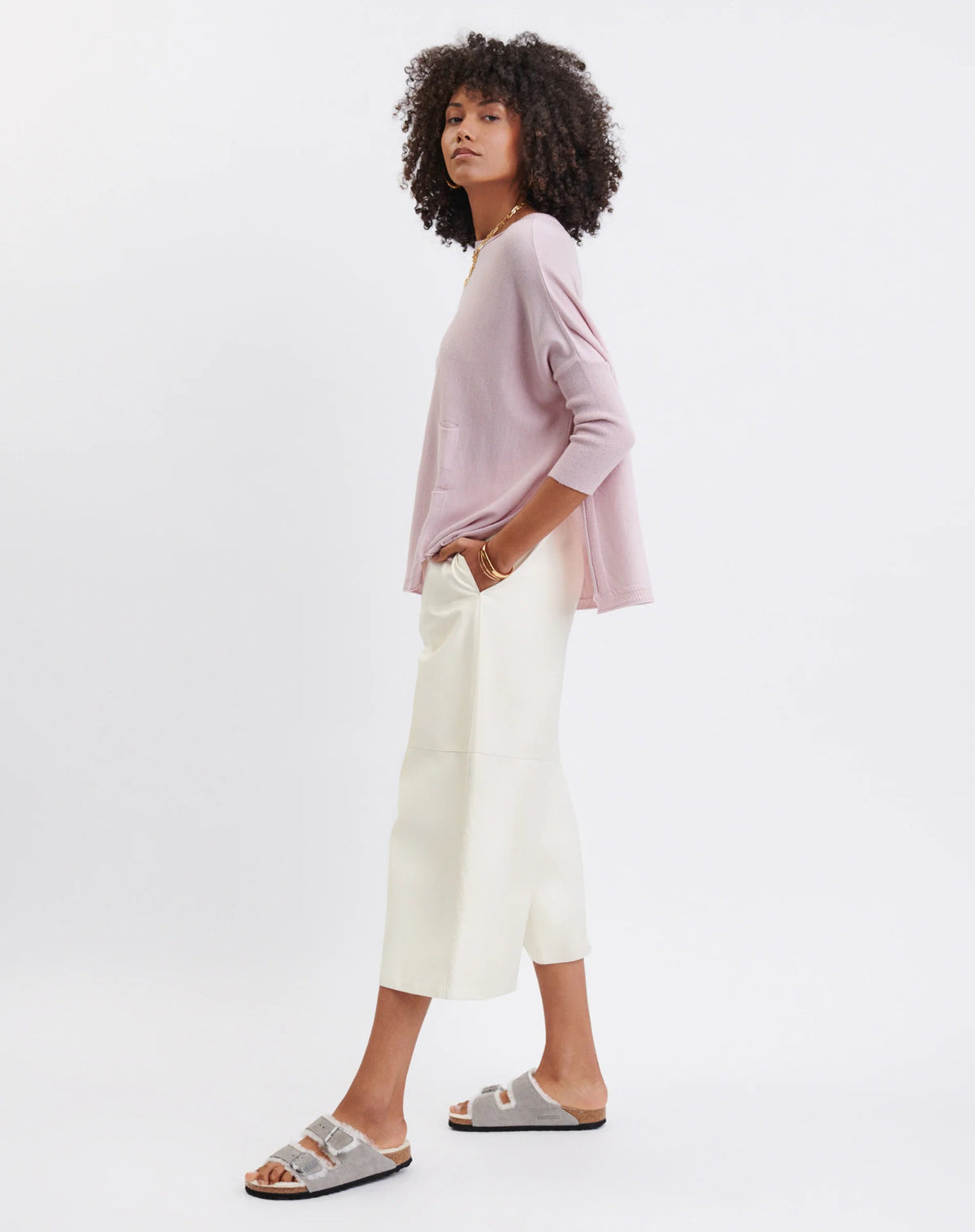 Woman wearing the MERSEA - CATALINA CREWNECK SWEATER, white with two black stripes, paired with denim shorts and a gold necklace—an essential piece from MERSEA for effortless, versatile style.